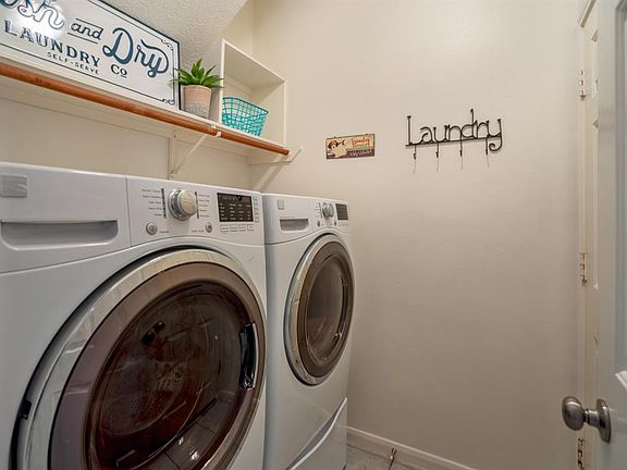 This large laundry room has great shelving space & a wall to wall hanging rack. Located in that sweet spot between the garage (door pictured to the right) and the foyer.