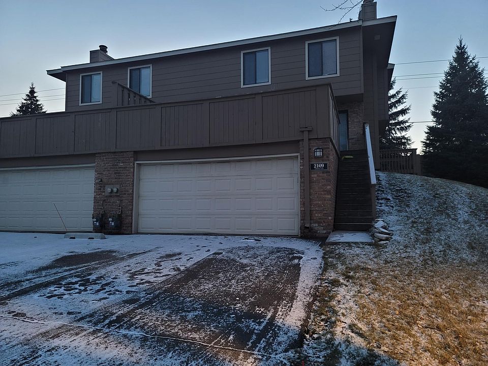 Garage, driveway, stairs going up to patio/main entrance