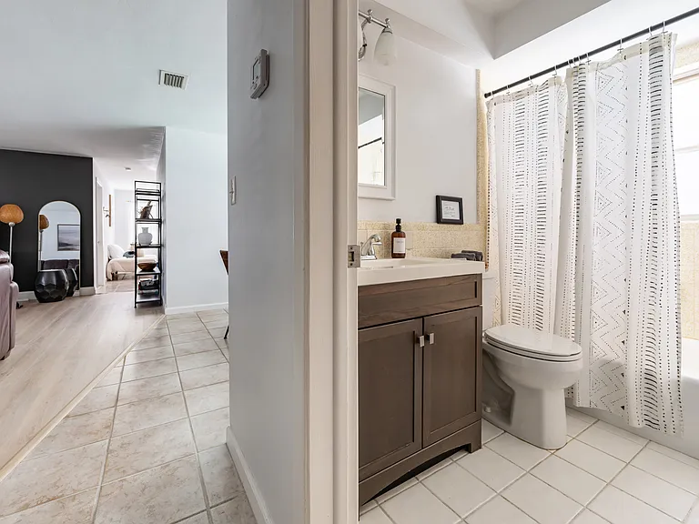 Off of the living room is the hallway bathroom with a tub.