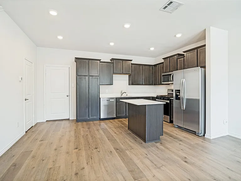 Kitchen featuring dark wood-finish cabinetry, stainless steel appliances, a center island with a marble countertop, recessed lighting, and wood-finish flooring