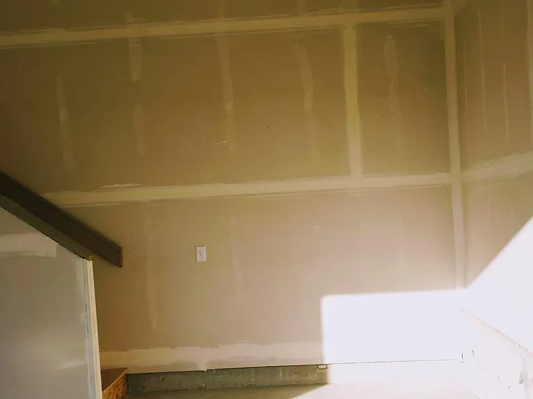 Looking into clean, attached garage. There is a steel storage shelving unit in here now.