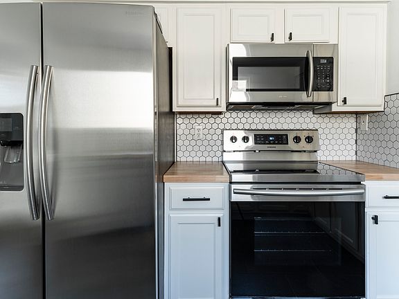 Updated kitchen with new butcher block countertops and backsplash.