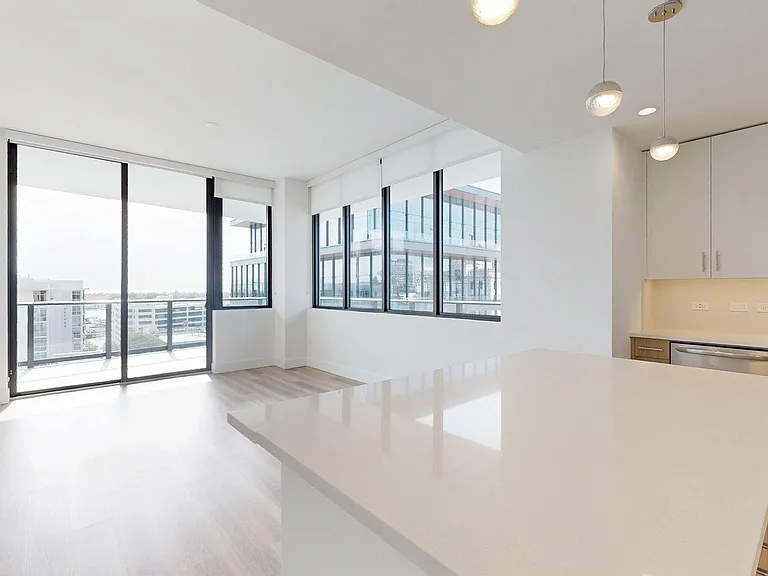 Apartment Kitchen with Stainless Steel Appliances, Dining and Living Room with hardwood floors.