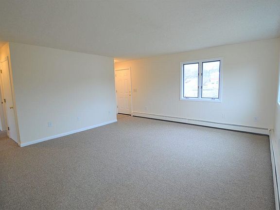 Large living room; front door to the right and bedrooms/bathroom down hallway on the left.
