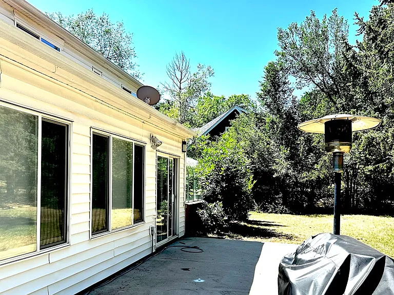 Outside back yard; sun room sliding doors at far end of picture; windows to family room are in the foreground. Notice BBQ and heat (included)