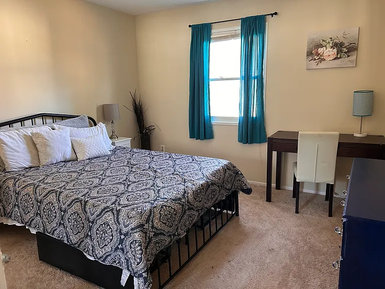 Master bedroom pictured here with queen sized bed, desk, and dresser.