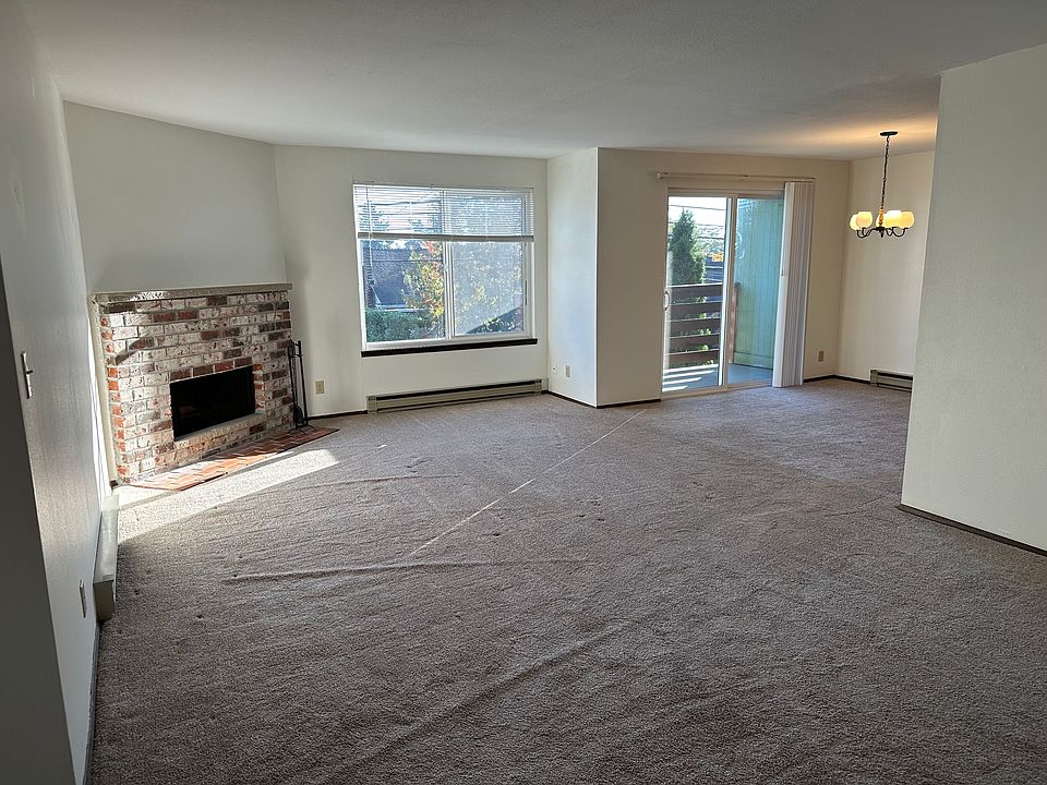 Sunny main room with fireplace, large windows, newer carpet.