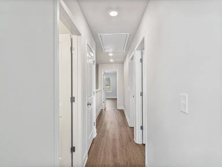 A bright hallway featuring warm wood flooring.