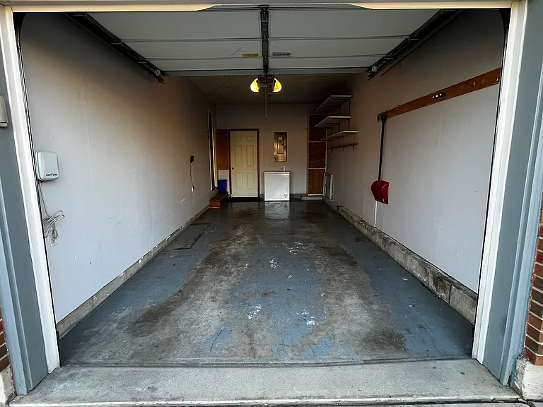 Single-car garage with chest deep freezer and baby gear for guest convenience.