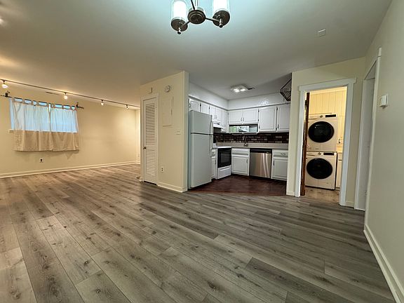 Open floor plan living/dining space with view of kitchen and bathroom entry.