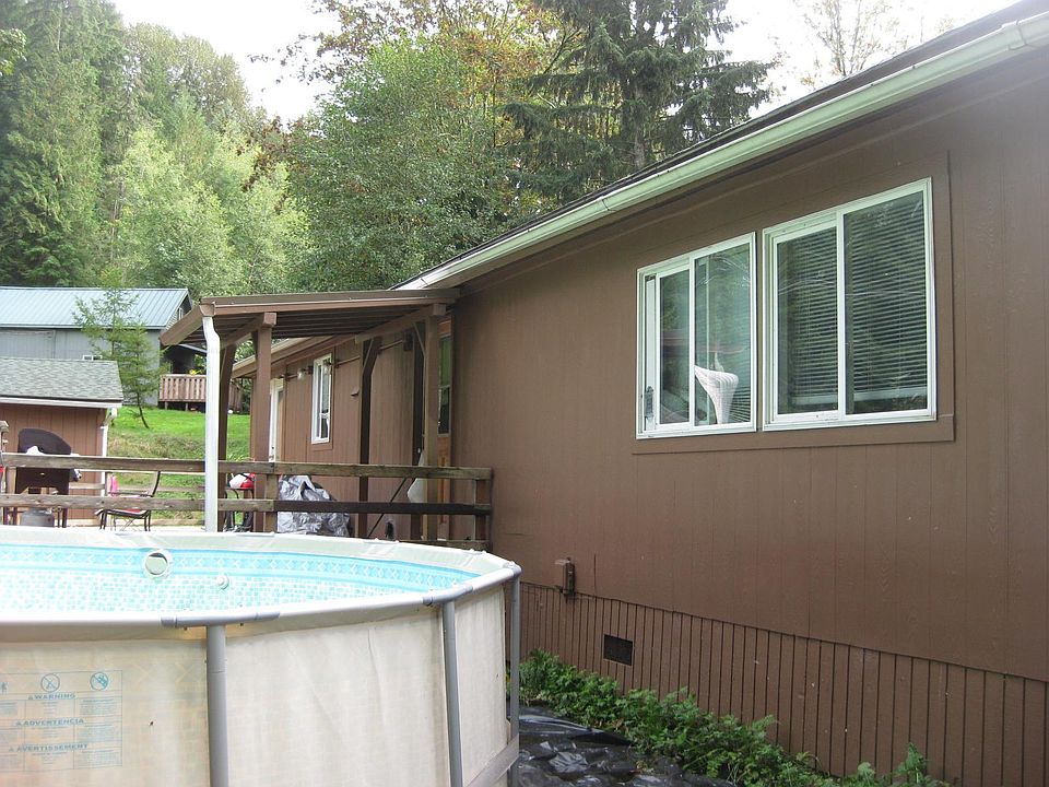 View of front of house from west end of yard. No swimming pool included. The roof covers the entrance to the laundry room.