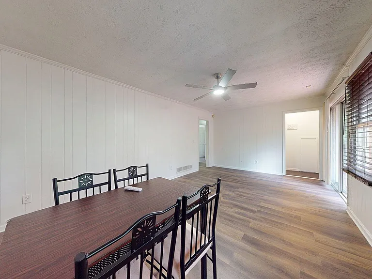 Open dining area with durable flooring, ceiling fan, and large windows with blindsideal for everyday meals and gatherings.