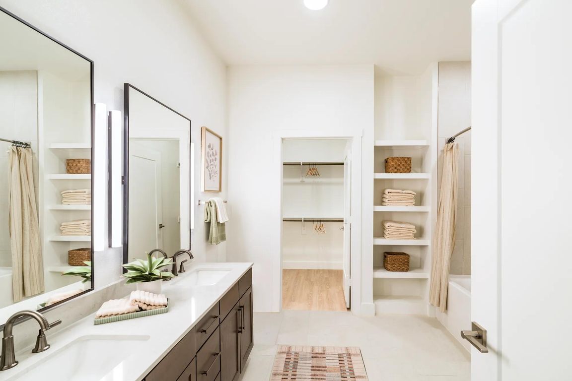 Spacious primary baths at Modera Trailhead feature dual vanities, open shelving, and seamless access to oversized closets.