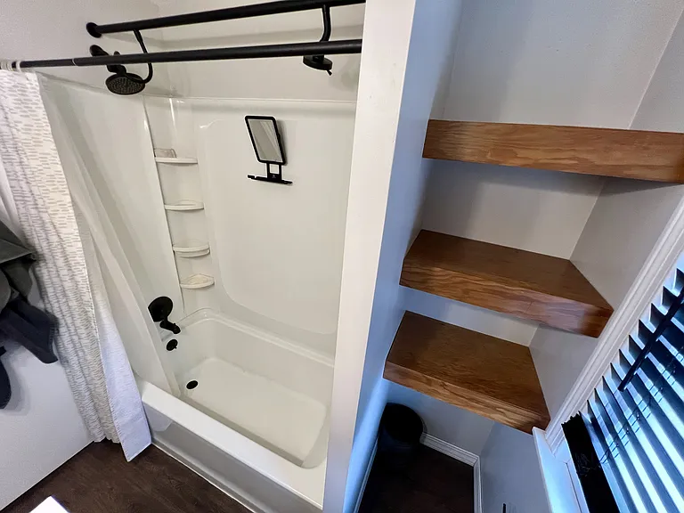 Bathroom with shelving. Additional closet for towels/toiletries in the hallway.