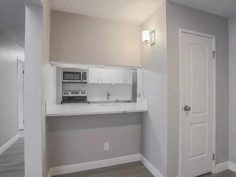 Modern kitchen nook with sleek countertops, integrated microwave, and ambient lighting in a cozy apartment setting.