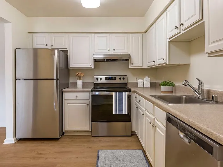 Renovated Woods I kitchen with stainless steel appliances, white cabinetry, grey laminate countertops, and hard surface flooring