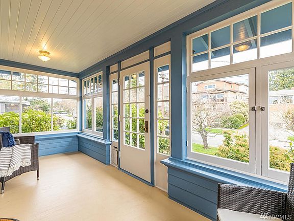 Original covered porch is wrapped in windows and finished with a tongue and groove ceiling. Note the original milk door at bottom left of the front door.