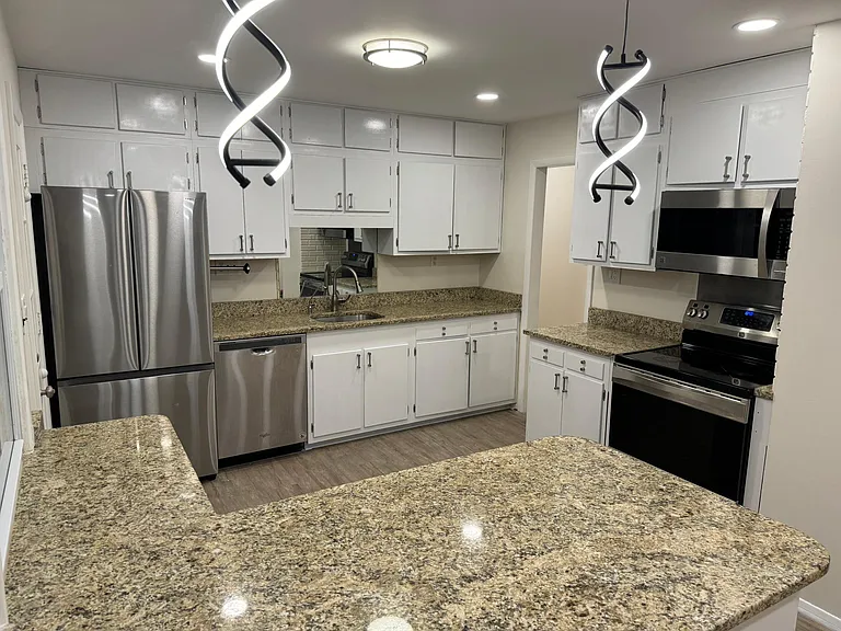 Kitchen with stainless steel appliances, pendant lighting, granite counter tops, white cabinets