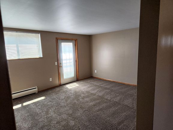 View of the living room showing the ground-level entry door coming in from the carport. New carpeting is shown.