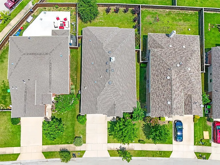 Aerial view showcasing a residential property with a shingled roof and a spacious concrete driveway