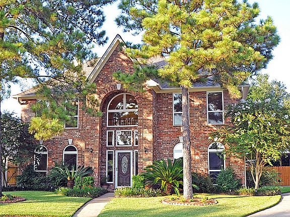 Another view of this wonderful home with large pine trees and flower beds.