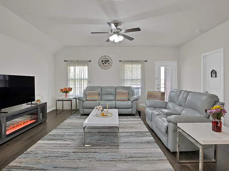 Oversized living area with ample natural light, vaulted ceiling, and ceiling fan