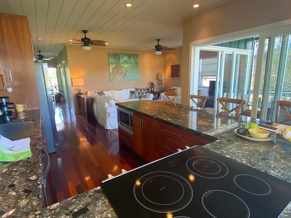 Kitchen opens into living area and lanai dining, surrounded by windows.