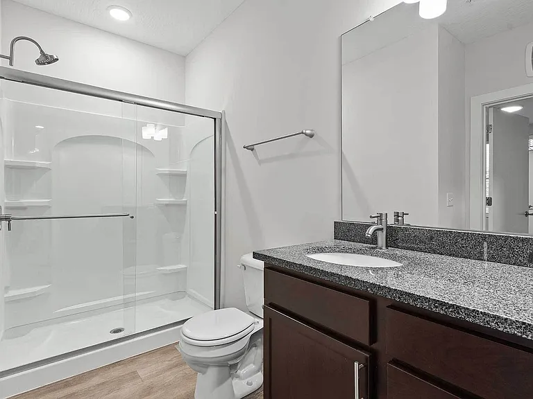The secondary bath features a glass-door shower, granite vanity, and modern fixtures _ complementing the upscale design throughout The Ave Apartments. The secondary bath features a glass-door shower, granite vanity, and modern fixtures _ complementing the