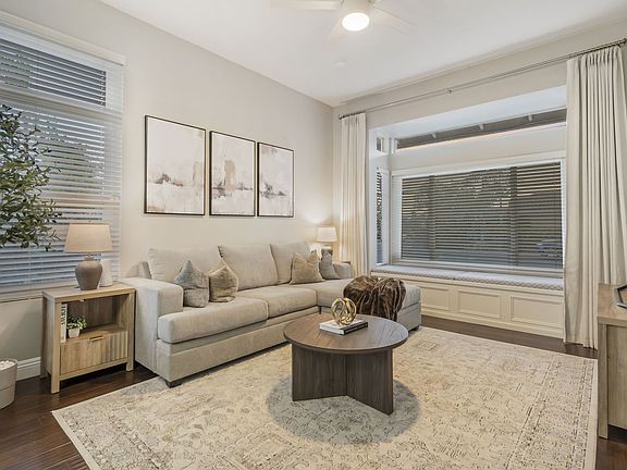 A cozy living room features a pull-out queen sofa bed, perfect for guests, and a 65" Smart TV for entertainment. It has a charming window seating area and side tables equipped with charging stations, offering convenience and comfort for everyone
