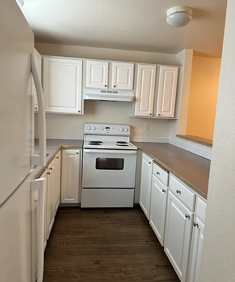 Updated kitchen with plank vinyl flooring, new countertops, and white appliances.