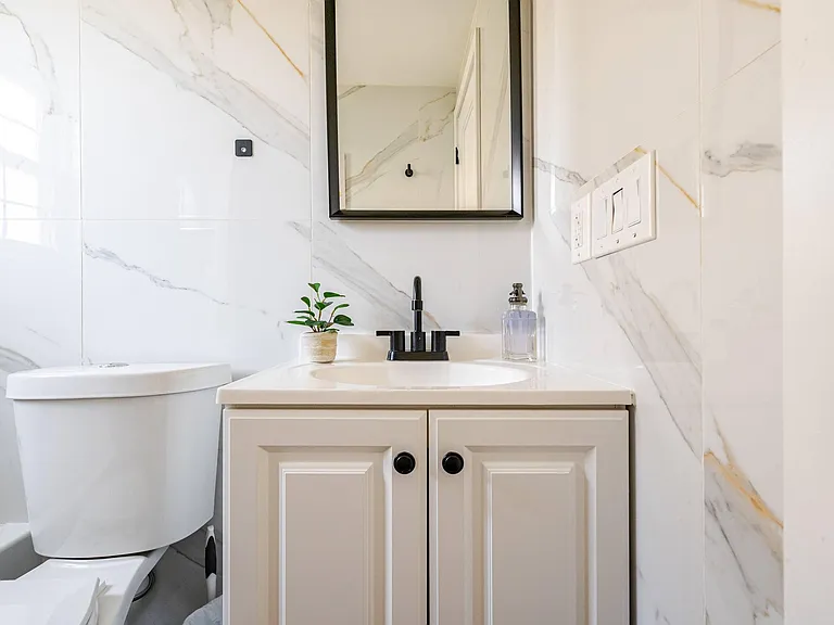 Updated bathroom vanity with storage, sleek black fixtures, and a mirrored cabinet above for everyday convenience.