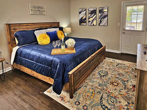Relax in this farmhouse-style bedroom. There is a king bed along with a flat-screen smart TV. Step out the door to the back patio and fenced-in backyard.