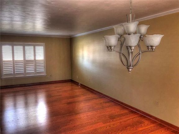 Dining area overlooks the living room with beautiful wood accents from the floor and lighting from the chandelier and patio door