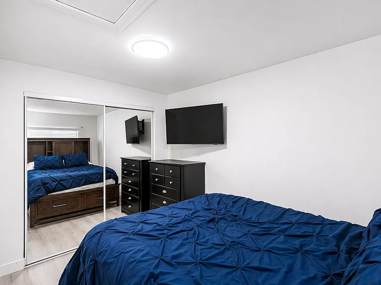 Spacious bedroom with dresser, mirror, and TV setup