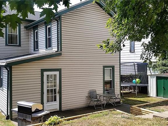 Back yard with large tree shading the back patio and fenced in yard.
