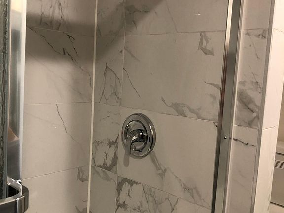 Brand new Calcutta tile in bathroom, new bathtub sliding doors, new shower head and brand new toilet