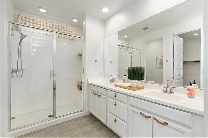 Private ensuite bathroom with dual vanity and walk-in shower with removable handheld wand for added comfort. Bath towels included. Shampoo, conditioner, and body wash available for shorter stays.