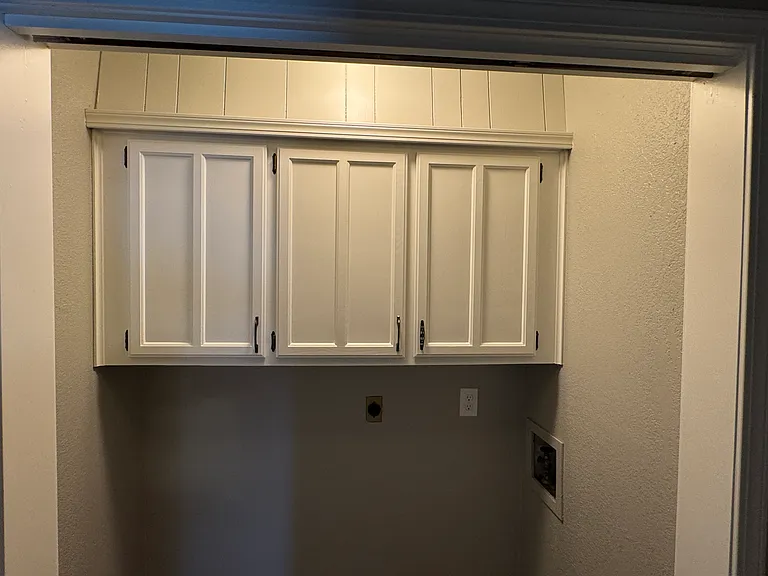 Utility room with hookups, storage cabinets.