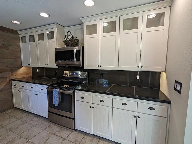 Kitchen with black granite counters, microwave, and range with flat cooktop.