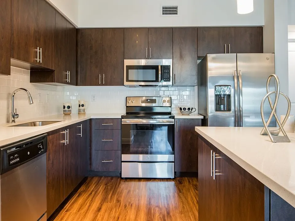 Kitchen with oak cabinetry, white countertops, white tile backsplash, and stainless steel appliances