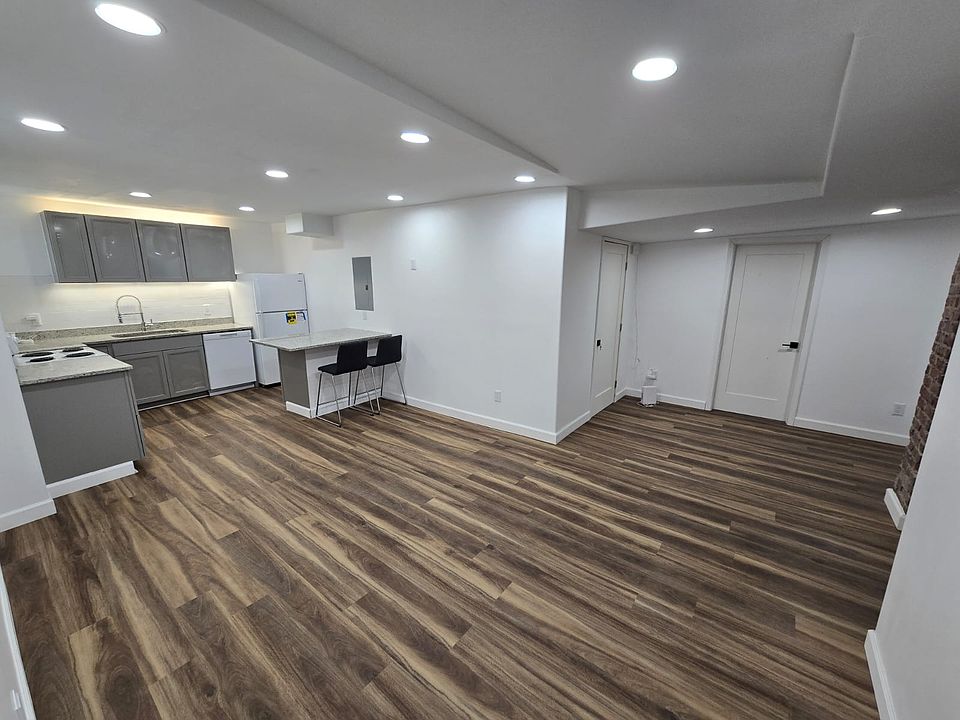 Modern open-concept living space with sleek kitchen featuring grey cabinetry and all new appliances. Beautiful stylish vinyl plank flooring, ample lighting, and adjacent dining area. Perfect blend of style and functionality.