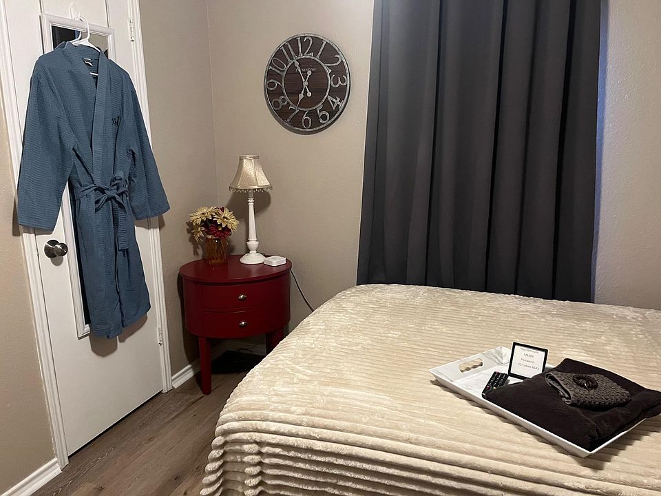Furnished bedroom with a comfortable bed, nightstand lighting, and window coverings for added privacy.