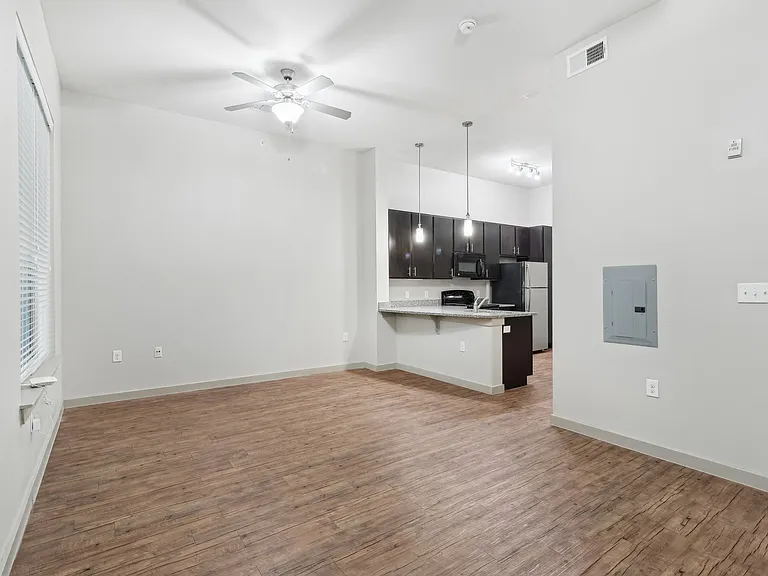 A room with a ceiling fan and wooden flooring.