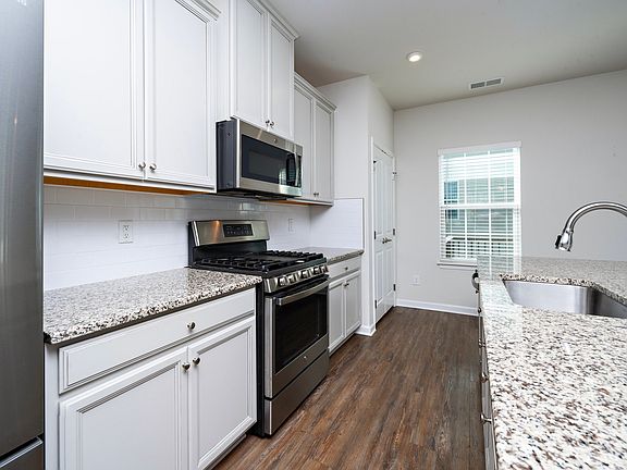 Stainless steel appliances, chef-style gas stove, large island with granite countertops, tall cabinets and large pantry