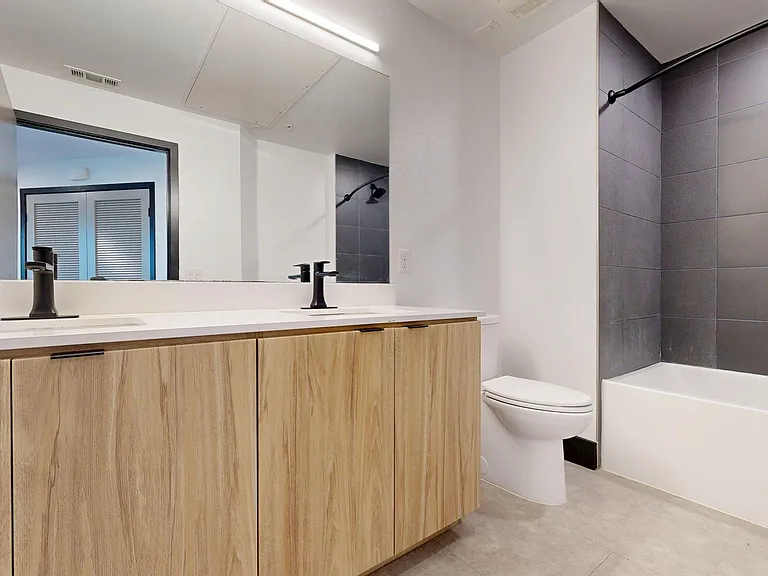 Apartment Bathroom with large soaking tub, vanity mirror and Wood-Style Flooring.