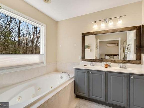 Owner's Bath with jetted tub, double sink, closet, and tile shower with bench