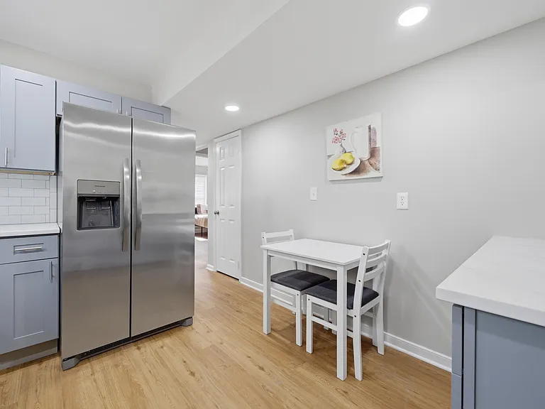 Eat-in kitchen area with stainless steel side-by-side fridge, ample cabinetry, and a compact dining nook for two.