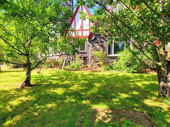 Large front yard and house hidden by leafy trees