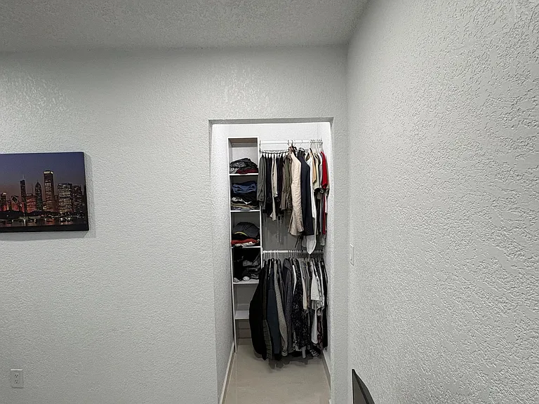 Private sleeping area with a built-in open closet system offering shelving and hanging space for organized storage.