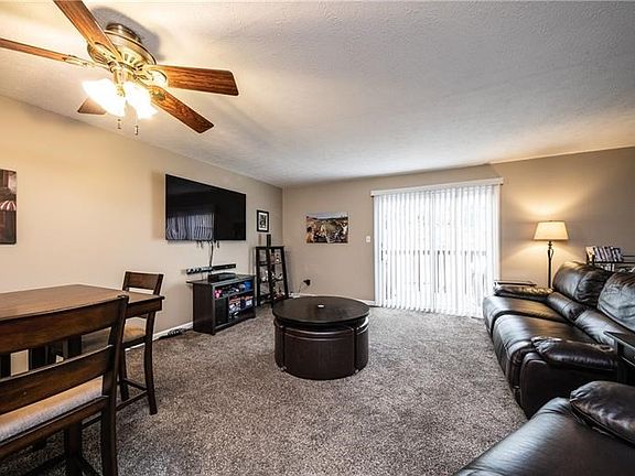 Living room with newer carpeting, freshly painted neutral walls and sliding door to rear deck.